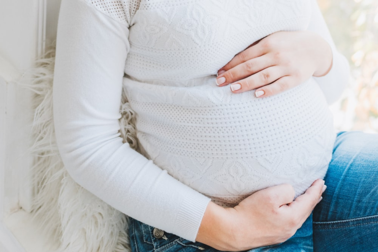 A pregnant lady sitting on a comfy bed