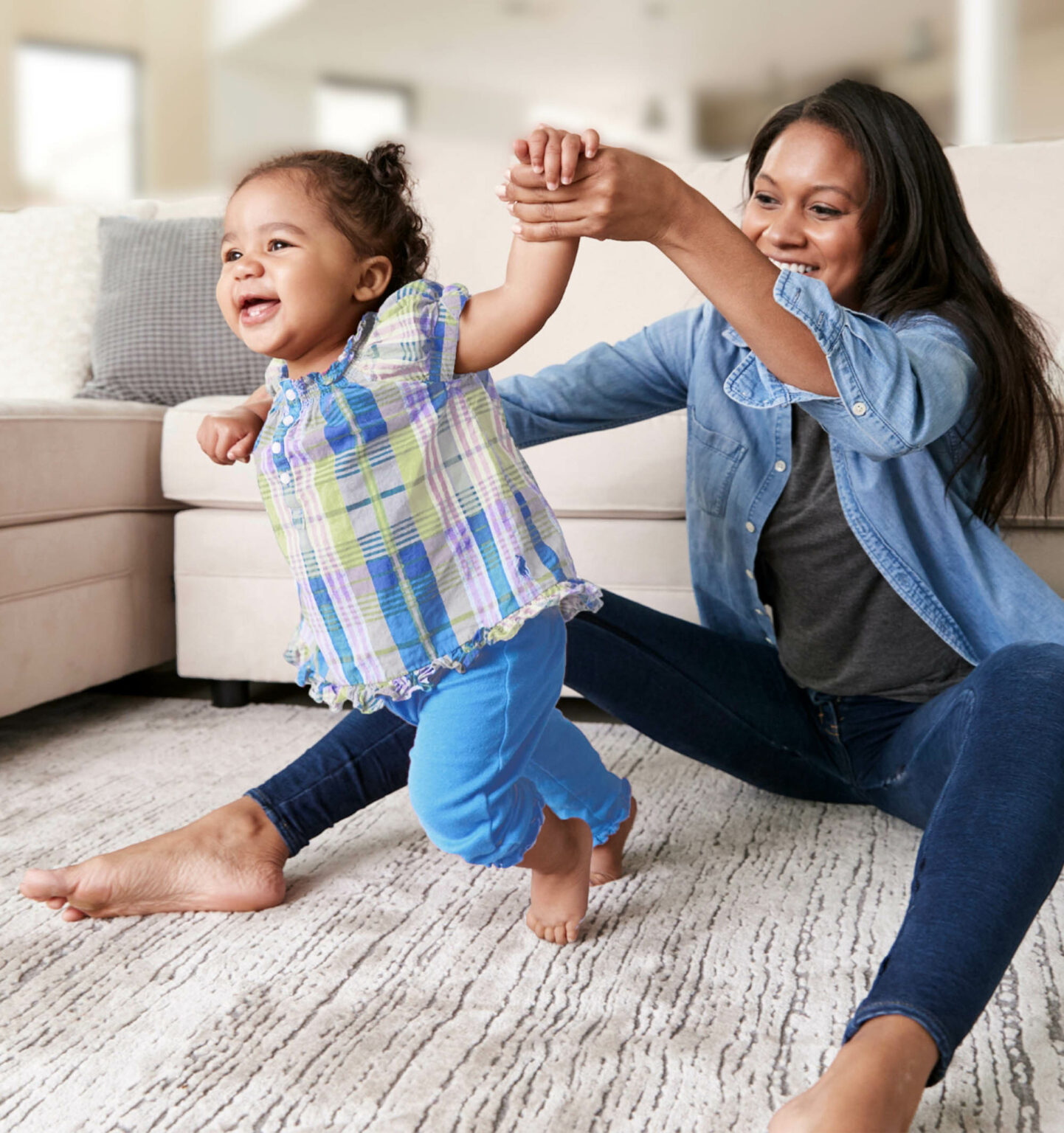 A mother holding her babies hand as she takes her first steps at home