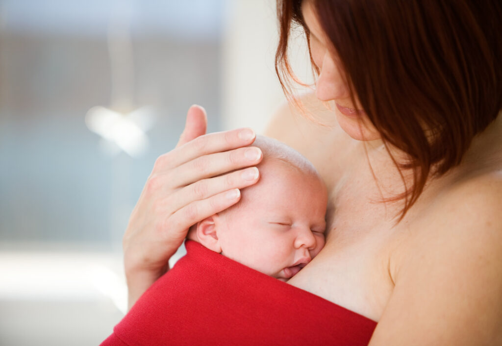 Mother gently holding sleeping baby girl. Skin to skin