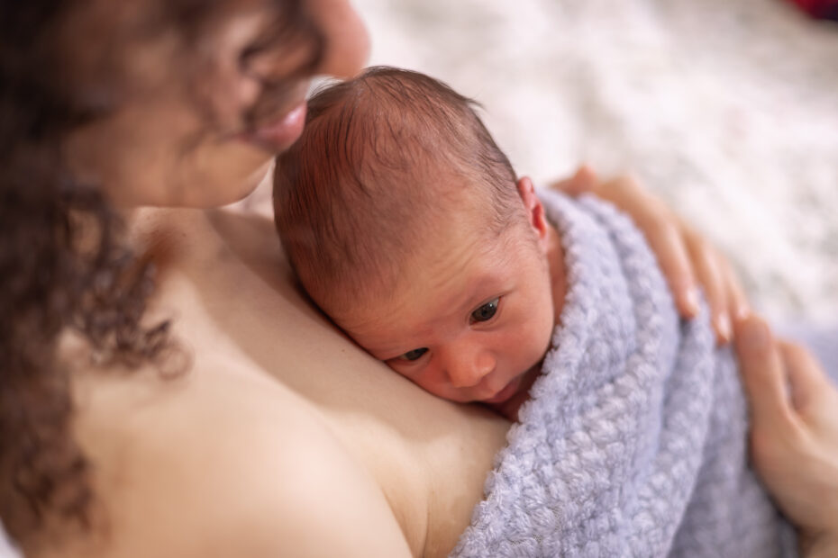 Healthy new born baby boy laying on mother chest. Skin to Skin