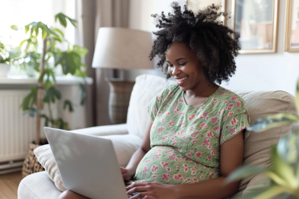 Pregnant woman smiling while using her laptop at home